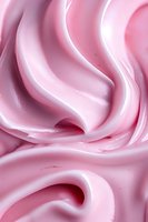Smooth swirls of pink cream create soft waves and curves in macro photography, showing delicate texture and glossy surface suitable for cosmetic or culinary designs.