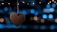 Wooden heart ornament hanging against blurred blue bokeh lights background, creating romantic mood for Valentine's day, weddings, or love celebrations.