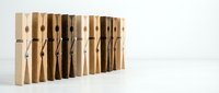 Row of wooden clothespins in various natural shades arranged in a line on a white surface, showcasing diversity in warm earth tones.