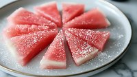 Fresh watermelon triangles arranged in a circular pattern on gray ceramic plate, juicy pink flesh with crisp white rind and natural texture, healthy summer fruit.