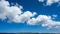 Dramatic blue sky with fluffy white clouds over calm ocean horizon creating peaceful seascape for nature backgrounds and travel content.