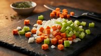 Fresh diced vegetables including carrots, celery and onions on dark slate board for cooking preparation and culinary recipes.