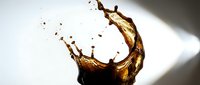 Dynamic coffee splash with golden brown liquid creating elegant curved motion against clean white background for beverage advertising and cafe marketing.