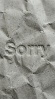 Word sorry embossed on crumpled gray paper texture, conveying apology and regret for greeting cards and emotional messaging concepts.