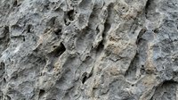 Close-up of rough stone surface with natural texture and weathered cracks, suitable for backgrounds, overlays, and architectural design projects.