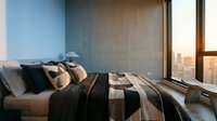 Modern bedroom with king-size bed featuring black and tan striped bedding and decorative pillows, floor-to-ceiling windows overlooking city skyline at sunset, minimalist interior design.