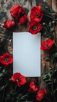 Vibrant red poppies frame blank white paper on rustic wooden background, creating romantic floral composition for wedding stationery or memorial design.