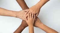 Diverse group of hands stacked together in teamwork gesture showing unity, collaboration and partnership in business or community support concept.