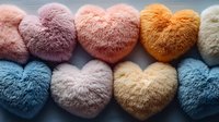 Colorful fluffy heart-shaped pillows arranged in rows showing pastel pink, orange, blue and cream soft textures for home decor and Valentine gifts.