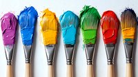 Colorful paint brushes arranged in rainbow order with vibrant purple, blue, yellow, turquoise, green, red and orange paint on white background for artistic design.
