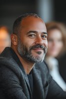 Confident middle-aged African American businessman with gray beard smiling warmly in modern office environment during corporate meeting or conference.