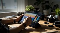 Creative professional using digital tablet for graphic design work at modern home office workspace with natural lighting and plants.