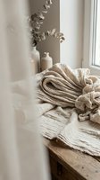 Cozy neutral linen fabric and eucalyptus branches on wooden surface near window creating warm minimalist home decor atmosphere for interior design projects.
