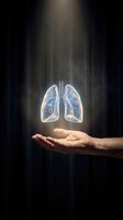 Human hand holding glowing transparent lungs with light beam from above on dark background for healthcare and respiratory medicine concepts.