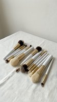 Professional makeup brush set with natural and synthetic bristles arranged on white linen fabric for beauty and cosmetics applications.