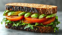 Fresh avocado and tomato sandwich on artisan bread with greens, healthy vegetarian meal concept for restaurant menus and food blogs.