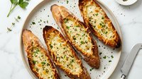 Baked potato boats filled with melted cheese and fresh herbs on white plate. Comfort food appetizer ready for serving at dinner party or restaurant menu.