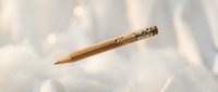 Wooden pencil with eraser floating against soft bokeh background with warm golden light effects for creative writing and education concepts.