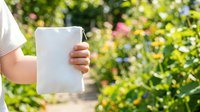 Caucasian child holding blank white mug outdoors in sunny garden with blooming flowers, ideal for beverage branding, product mockups, and promotional campaigns.