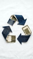 Recycling symbol made from upcycled denim fabric scraps and organic cotton patches arranged in circular arrows on white background, representing sustainable fashion and circular economy concepts.