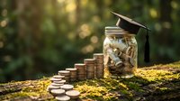 Education savings fund concept with graduation cap on coin-filled jar and stacked coins on moss-covered log in natural outdoor setting for financial planning.