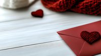 Red envelope with knitted heart decoration on white wooden background, romantic message concept for Valentine's Day, anniversaries, and love letters.