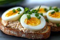 Fresh hard-boiled eggs on whole grain bread with green herbs make a nutritious breakfast or snack option for healthy eating and meal preparation.