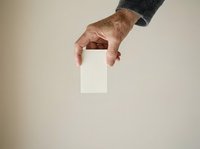 Mature male hand holding blank white card against neutral background for business messaging and corporate branding applications.