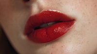 Close-up of woman's lips with glossy red lipstick and natural skin texture for beauty and cosmetics advertising campaigns.