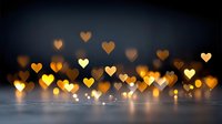 Romantic heart-shaped bokeh lights creating warm golden glow against dark background for Valentine's Day celebrations and love-themed designs.