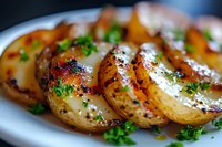 Roasted golden potatoes garnished with fresh parsley and black pepper, served on white plate with selective focus creating appetizing depth of field.