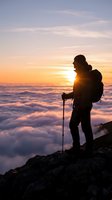 Silhouette of hiker with backpack and trekking pole standing on rocky mountain peak above sea of clouds at sunrise, adventure and outdoor exploration concept.