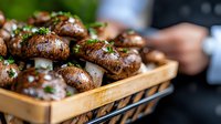 Fresh brown mushrooms garnished with chopped herbs and sea salt served in wooden box, close up view with selective focus. Restaurant appetizer presentation.