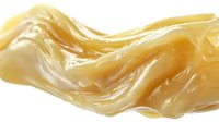 Smooth flowing honey caramel liquid wave on white background, glossy golden syrup stream with soft ripples and curves, isolated design element for food packaging.