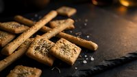 Homemade shortbread cookies dusted with sugar and cinnamon arranged on dark slate surface with warm lighting, suitable for food photography, baking blogs, and culinary content.