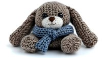 Adorable knitted brown bunny toy with long floppy ears wearing blue scarf on white background, handmade crochet stuffed animal isolated for craft and design projects.