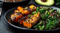 Grilled sweet potato wedges with quinoa spinach salad on dark plate. Healthy vegetarian meal with roasted vegetables and leafy greens for nutritious dining.