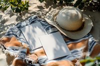 Relaxing outdoor reading setup with open book, straw hat and cozy blanket under dappled sunlight for peaceful leisure moments.
