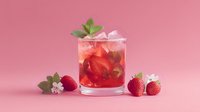 Refreshing strawberry cocktail with mint garnish and ice cubes in glass on pink background, perfect for summer drinks menu and beverage photography.
