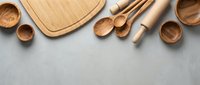 Wooden kitchen utensils and cutting board arranged on gray surface with copy space for cooking and food preparation concepts.