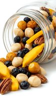Mixed nuts and dried fruits spilling from glass jar on white background. Includes macadamia nuts, pecans, raisins, blueberries and mango strips. Isolated for packaging, recipe blogs and healthy snack marketing.