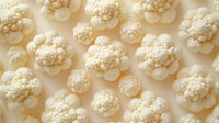 Fresh cauliflower florets pattern on beige background, organic healthy vegetable texture for food industry and healthy eating concept design.