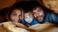 Happy family with young child snuggled under warm blanket sharing intimate moment together. Close up portrait showing genuine emotions and connection in cozy atmosphere.