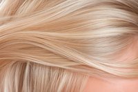 Silky smooth blonde hair texture with gentle waves showing natural highlights and lowlights, close-up view demonstrates healthy shine and movement.