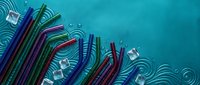 Colorful reusable metal drinking straws with cleaning brushes on turquoise background with water ripple effects for eco-friendly lifestyle and sustainability.