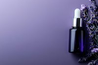 Dark blue glass dropper bottle with fresh lavender sprigs on purple background, elegant composition for aromatherapy and natural cosmetics marketing.