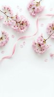 Pink cherry blossom branches with scattered petals and silk ribbon on white background for spring wedding invitations and romantic designs.