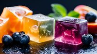 Colorful fruit jelly cubes with fresh berries and mint leaves on dark background. Sweet dessert gummies in orange green purple flavors for confectionery packaging.