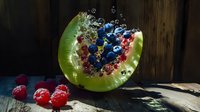 Fresh watermelon slice with floating blueberries and raspberries in water splash effect against rustic wooden background, dramatic lighting creates dynamic food scene.