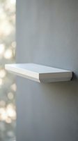 White floating shelf mounted on gray wall with soft natural light creating bokeh effect for modern minimalist interior design.